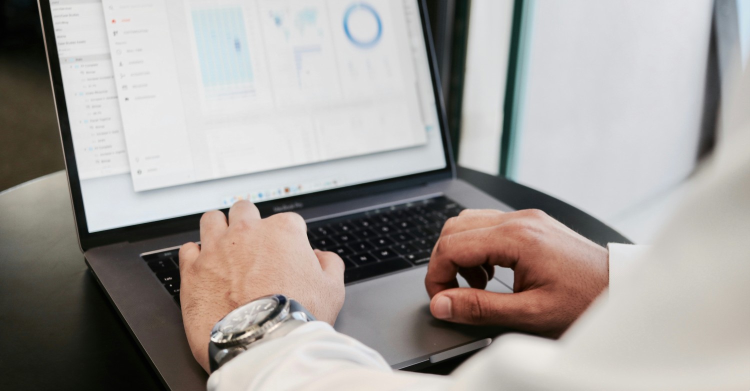 Hands typing on a laptop displaying a business dashboard